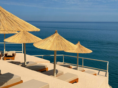 Beach lounge chairs and  sun umbrellas on sea shore.