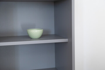 Green ceramic bowl on gray shelf. Simplicity, calm color harmony, and order in modern home design. Copy space