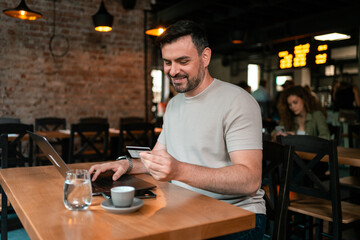 Enjoying coffee while making online purchases at a cozy cafe during the morning hours