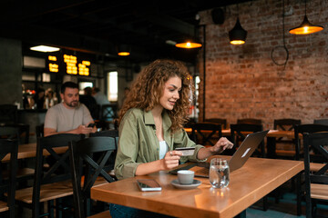 Young woman working on laptop in a cozy cafe during the afternoon