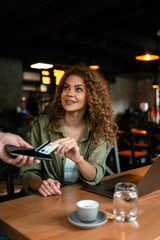 Woman enjoys conversation at cafe while receiving payment for service