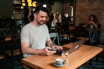 Focused professional using a laptop and smartphone at a modern cafe during the afternoon