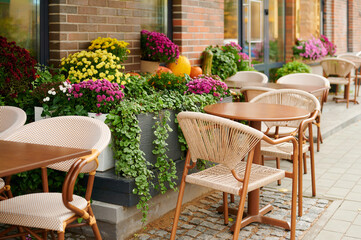 charming outdoor cafe featuring wooden tables surrounded by vibrant potted plants on cobblestone walkway. inviting seating area perfect for al fresco dining or relaxed coffee breaks.