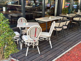 Outdoor cafe tables and chairs waiting for guests on a wooden deck. Calm atmosphere, urban leisure, and the rhythm of daily city life.