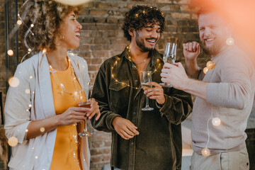 A group of friends dancing with raising glasses of champagne on the Happy New Year party
