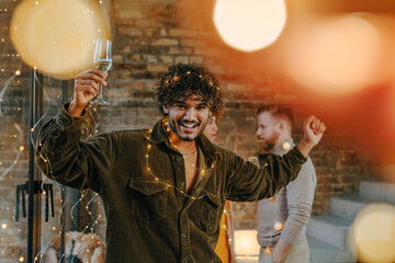 A group of friends dancing with raising glasses of champagne on the Happy New Year party