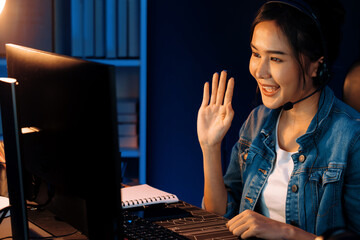Host channel Asian influencer talking in broadcast streaming online wearing headsets on social media with pc recording, greeting listeners and coaching market online at neon modern studio. Stratagem.