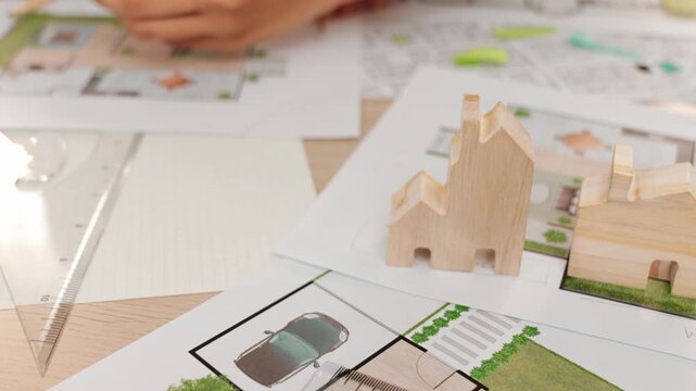 Smart architect and safety engineer discussion about building blueprint on table with architectural document, measurement tools and wooden block scatter around at modern office. Closeup. Delineation.