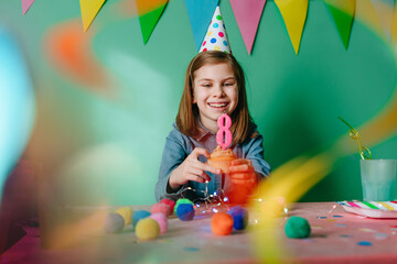 Happy smiling girl celebrating eight birthday sitting at a table