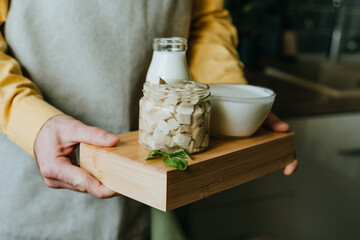 Close up of man holding wooden tray with tofu, yogurt and milk