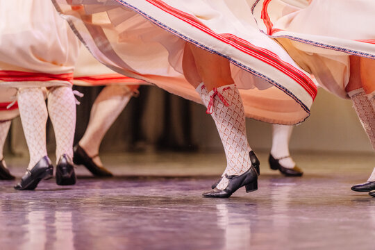 Latvian folk dancers showcase vibrant traditional costumes while performing lively dance steps on stage, capturing cultural heritage and joyful expression - Powered by Adobe
