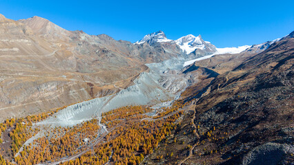 A drone view above Zermatt reveals the stunning Matterhorn region with its famous lakes, golden larches, and a deep blue autumn sky in perfect harmony.