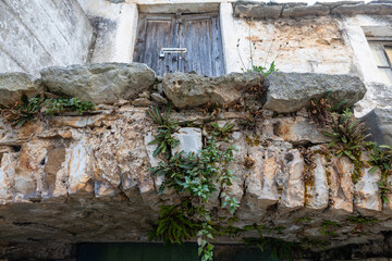 Weathered Stone Balcony With Plants And A Wooden Door Above A Crumbling Wall