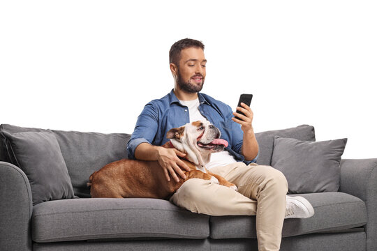 Young man resting on a sofa with his pet dog and using a smartphone - Powered by Adobe