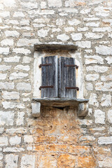 Weathered Wooden Door Shutters Set in a Cracked Stone Wall, Creating a Rustic Vintage Exterior