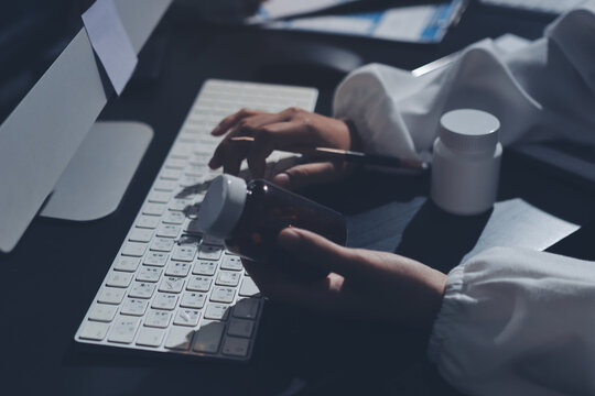 Two doctors and a female nurse meet at a table in the hospital, collaborating on medical tasks using laptops and computers - Powered by Adobe