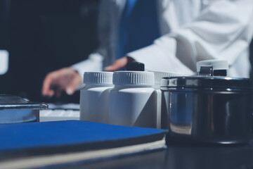 Two doctors and a female nurse meet at a table in the hospital, collaborating on medical tasks using laptops and computers