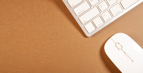 Computer keyboard and mouse on brown background. Top view with copy space