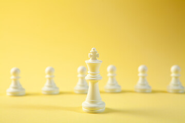 Chess business concept image with chess pieces on a yellow background.