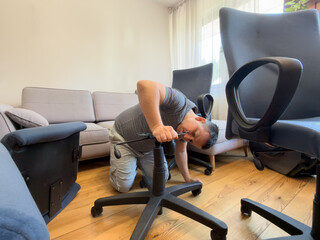 Man repairing an office chair in a bright living room