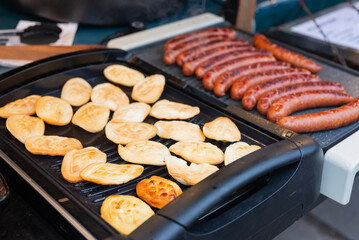 A chef grills sausages and national food, Polish cheese oscypek, at a Christmas fair.