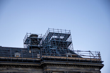 Scaffolding structure on a historic building under renovation, showcasing intricate architectural details and a clear blue sky, emphasizing construction and restoration efforts