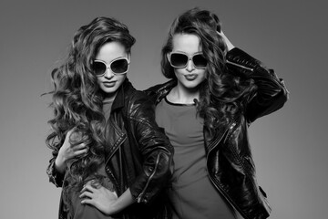 Sisters twins in hipster sun glasses laughing Two fashion models Women smiling positive Friends group having fun, talking Youthful friendship youth adults people culture concept Young girls rock party