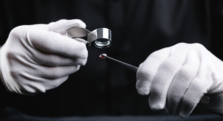 Jeweler analyzing diamond with magnifying glass and tweezers under soft light