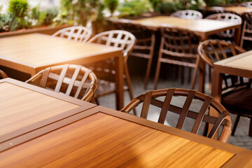 Outdoor cafe seating with wooden tables and chairs wicker tree back with sunlight
