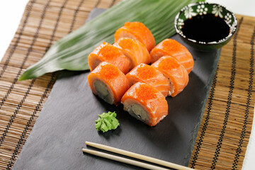 Delicious salmon sushi Philadelphia rolls with wasabi and soy sauce on slate plate