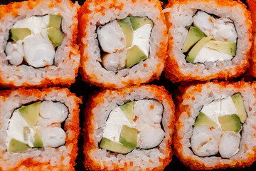 Closeup of california roll sushi with avocado, crab, and rice topped with tobiko, top view