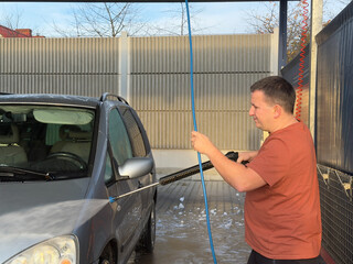 Man washing a silver car at a car wash