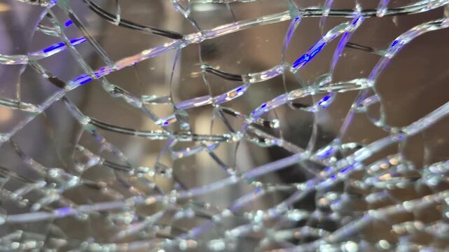 Broken cracked glass in closeup with pieces still intact shows a delicate balance of structure and visible crack patterns.