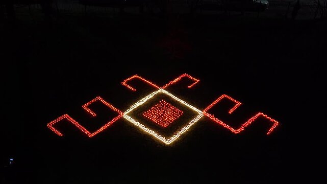 Illuminated geometric design featuring vibrant red and white lights, showcasing intricate patterns on the ground, with a gradual zoom out revealing the full scene