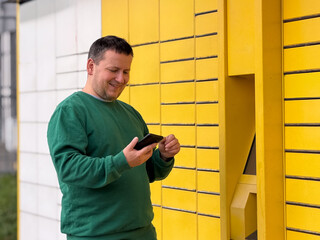 Man using smartphone near yellow wall