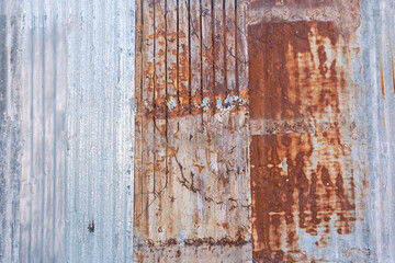 Rusty corrugated metal panels are recycled by piecing them together into a colorful fence. The...