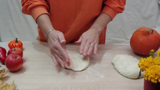 A girl is making apple pie at home. Autumn fall baking background with pumpkins, apples, nuts, food ingredients and seasonal spices. Cooking pumpkin or apple pie for Thanksgiving and autumn holidays, 