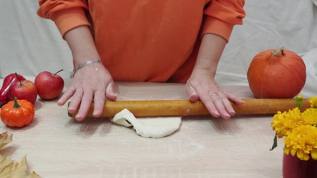A girl is making apple pie at home. Autumn fall baking background with pumpkins, apples, nuts, food ingredients and seasonal spices. Cooking pumpkin or apple pie for Thanksgiving and autumn holidays, 