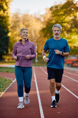 Obraz premium Mature couple of runners jogging in autumn day outdoors.