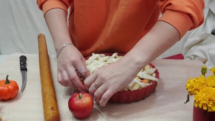 A girl is making apple pie at home. Autumn fall baking background with pumpkins, apples, nuts, food ingredients and seasonal spices. Cooking pumpkin or apple pie for Thanksgiving and autumn holidays, 