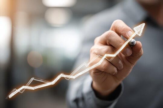 Hand drawing a radiant upward trend line on a transparent surface, depicting business growth.