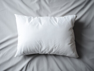 Soft white pillow resting on a smooth gray bedspread in a tranquil bedroom setting. Mockup
