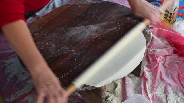 A woman quickly rolls and flattens dough for g&ouml;zleme (Turkish flatbread) using a traditional rolling pin. Preparing homemade village food.
