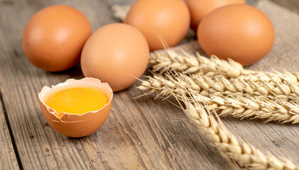 Freshly laid brown eggs and golden wheat ears on a rustic wooden surface, symbolizing natural goodness and healthy eating