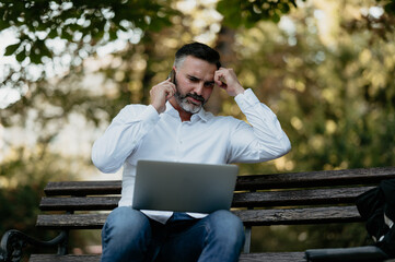 Fototapeta premium Mature man experiencing stress during remote work phone call