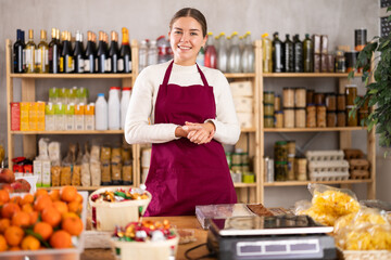 Portrait of female seller in an apron behind the counter of a grocery store