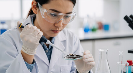young asian woman scientist analyzing soil sample in laboratory for environmental research