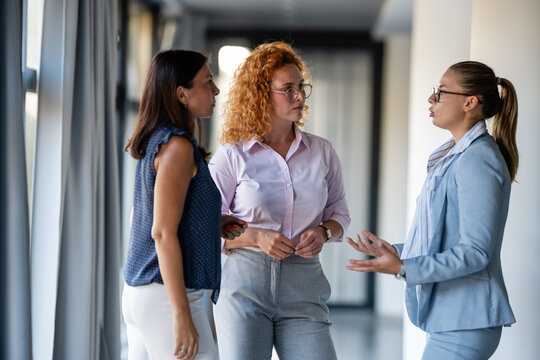 Group of businesswomen discussing ideas in modern office hallway