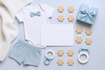 Fototapeta premium Flatlay of baby boy essentials, clothing, cookies, and a gift box on a blue background
