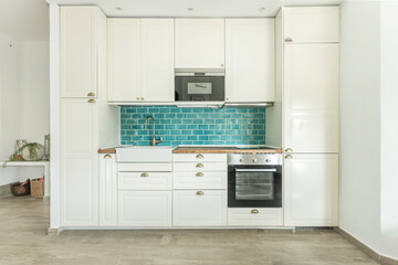 Image of a kitchen with Nordic-style cabinetry in light wood and leather handles, including a window above the sink with access to the patio